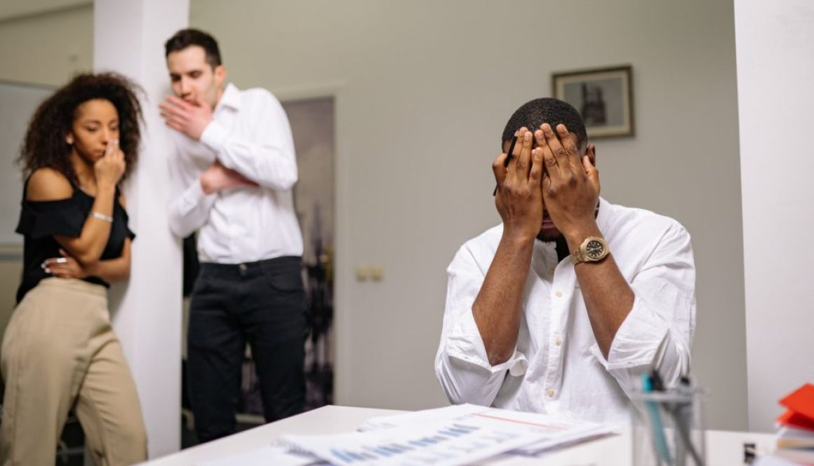 man in white dress shirt covering his face