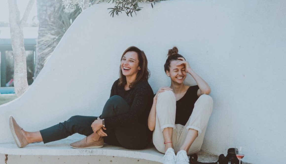 two women sitting on white bench