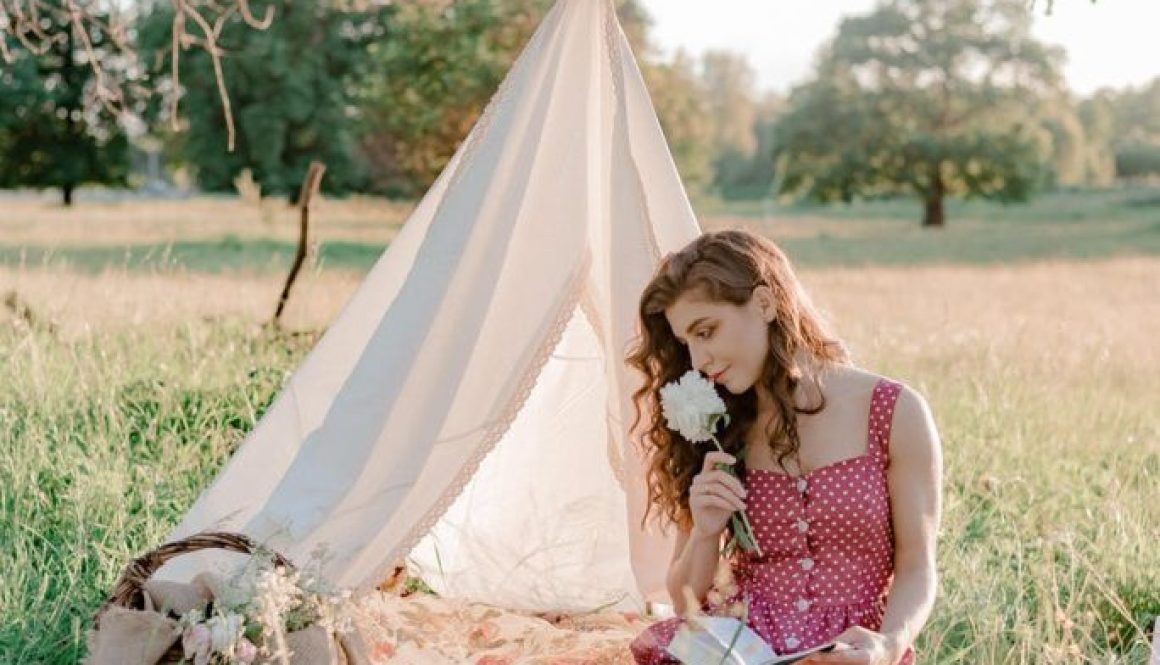 woman wearing polka dot dress smelling white flower