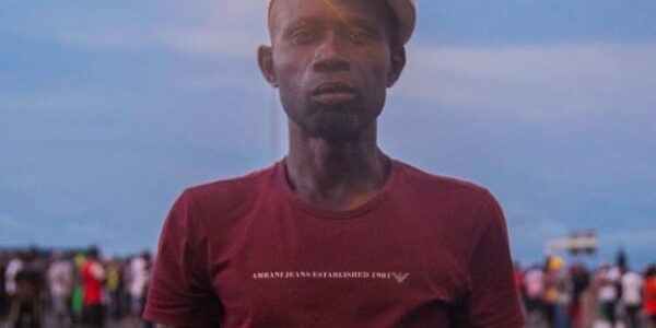 man wearing a hat holding a placard with a text stay woke