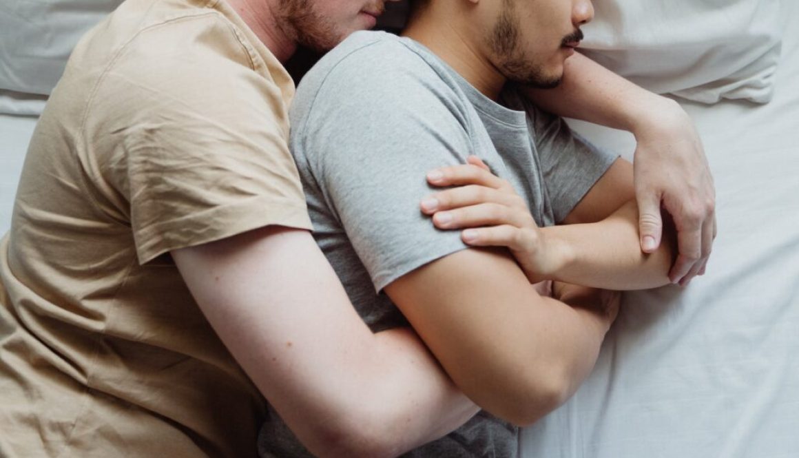 two men cuddling in bed