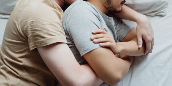 two men cuddling in bed